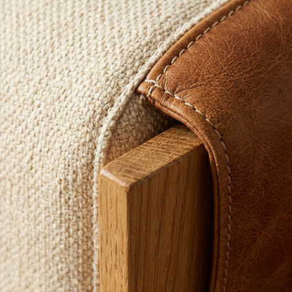 Close-up showing leather upholstery, stitched edging and a timber furniture frame